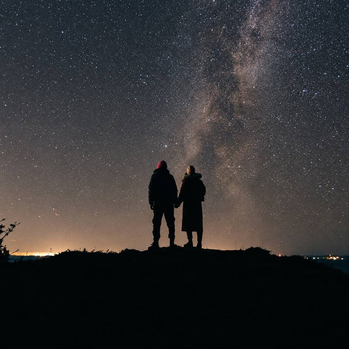 Deux personnes contemplent ensemble la Voie lactée sous un ciel étoilé.